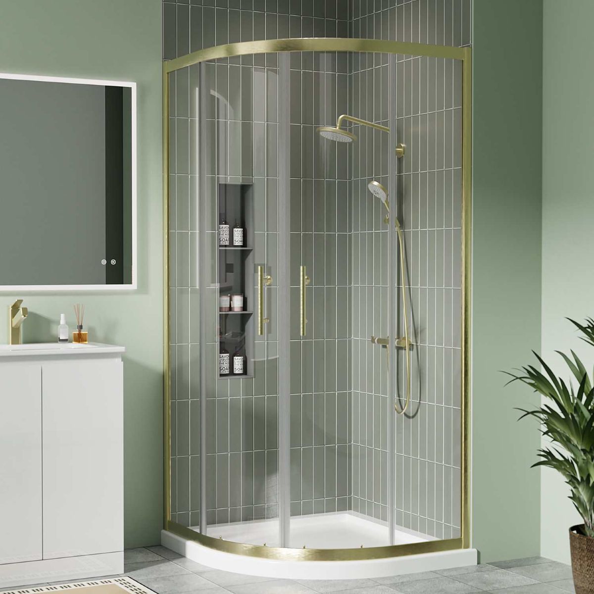 Brushed brass quadrant shower enclosure with sliding glass doors and white shower tray in a modern green-tiled bathroom.