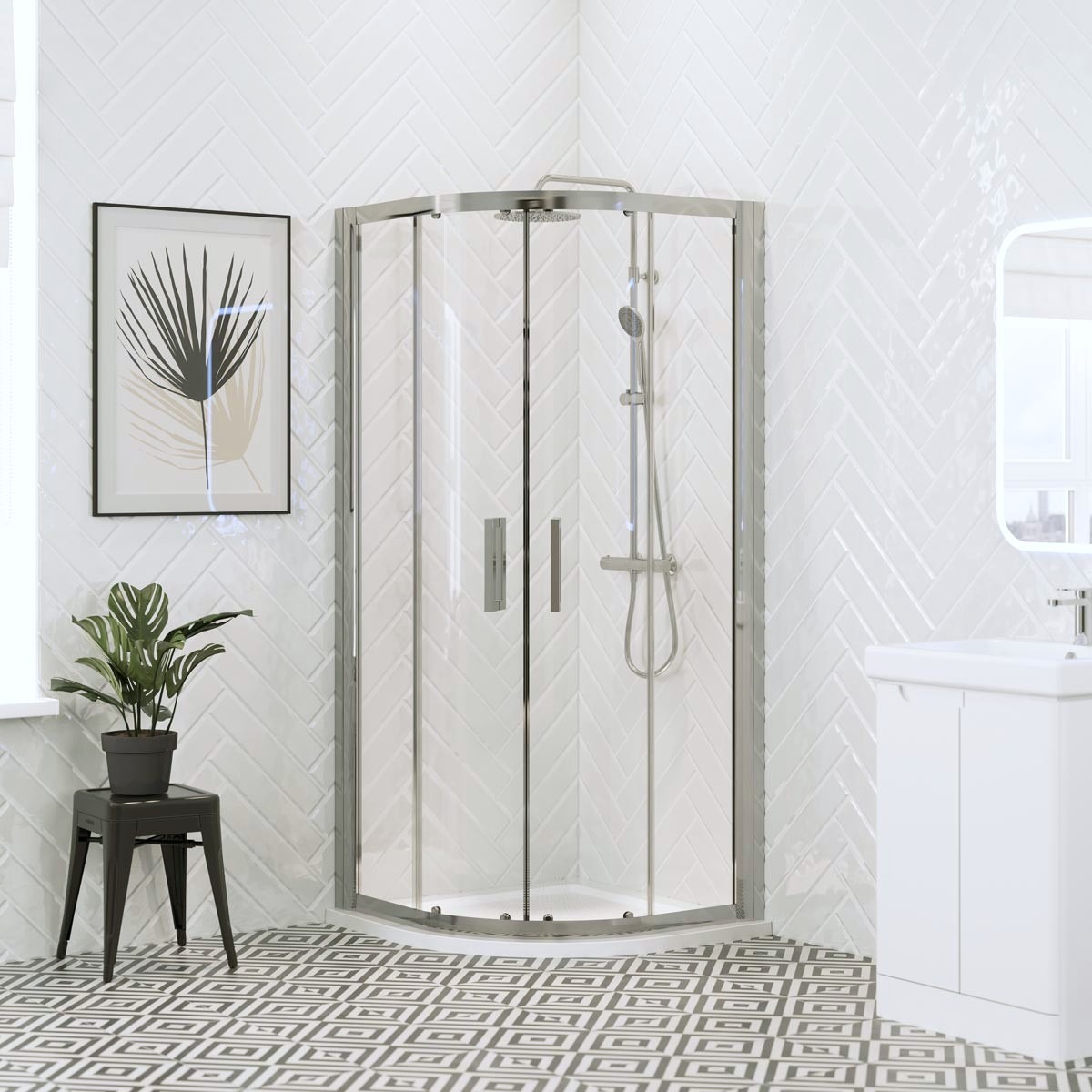 Chrome quadrant shower enclosure with sliding glass doors and white shower tray in a bright modern bathroom with white herringbone wall tiles.