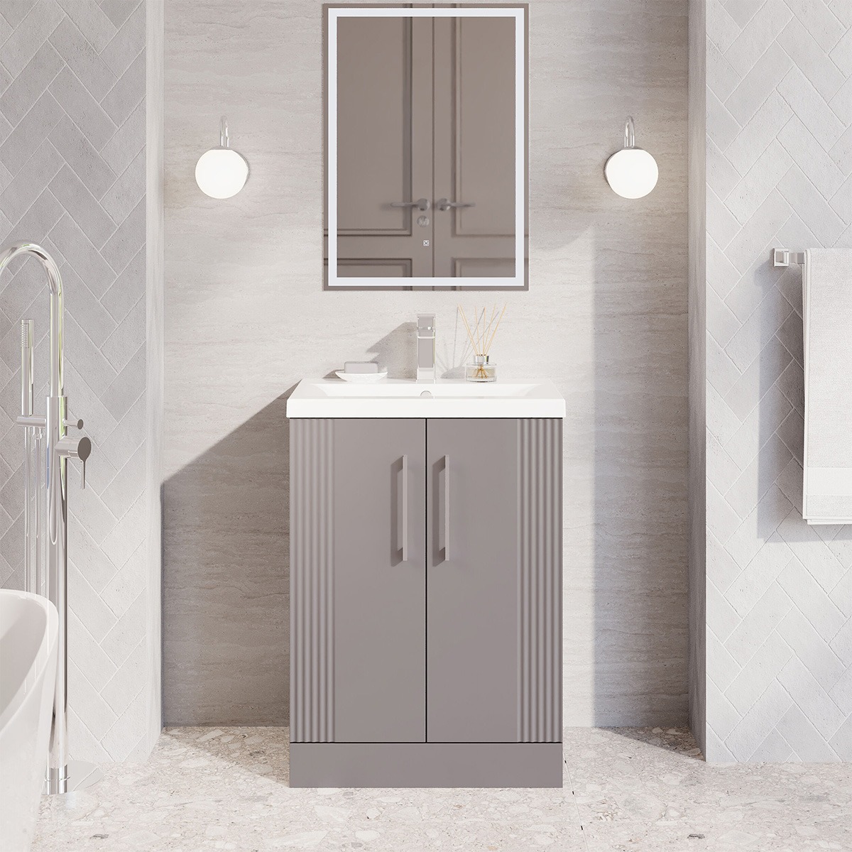 Deco 600mm Freestanding Unit in Satin Grey shown in a contemporary bathroom with neutral stone-effect walls, grey herringbone tiles and chrome fixtures.