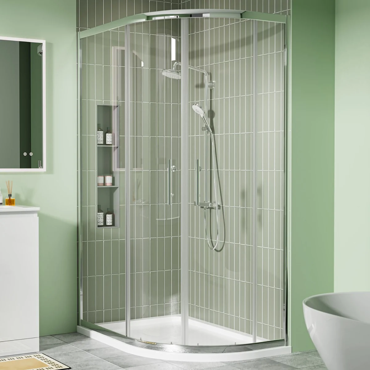 Chrome offset quadrant shower enclosure with sliding glass doors and white shower tray in a modern green-tiled bathroom.