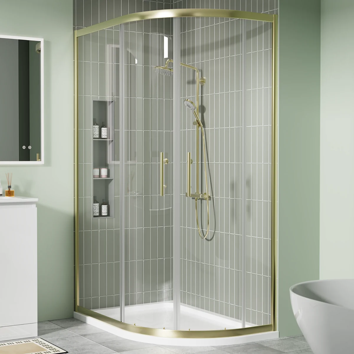 Brushed brass offset quadrant shower enclosure with sliding glass doors and white shower tray in a modern green-tiled bathroom.